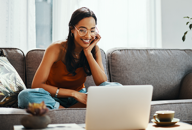 Young woman sitting on a couch looking at a computer