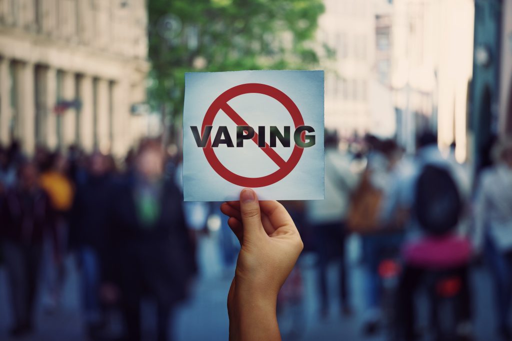 Hand holding a sign with a no vaping message on it